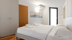 Une chambre à coucher comprenant un lit, une armoire, une porte et un climatiseur fixé au mur.