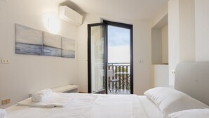 Une chambre d’hôtel avec un lit, un banc, un balcon et une vue sur le ciel.