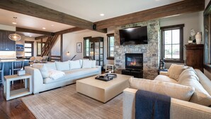 A spacious living room with a stone fireplace, a large flat-screen TV, and a cozy seating area.