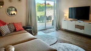 Un salon moderne avec un canapé, un téléviseur et une vue sur un balcon.