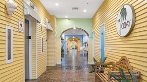A hotel corridor with yellow walls, a brick floor, and a wooden bench.