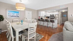 A modern kitchen with white cabinets, stainless steel appliances, and a bar area with stools.