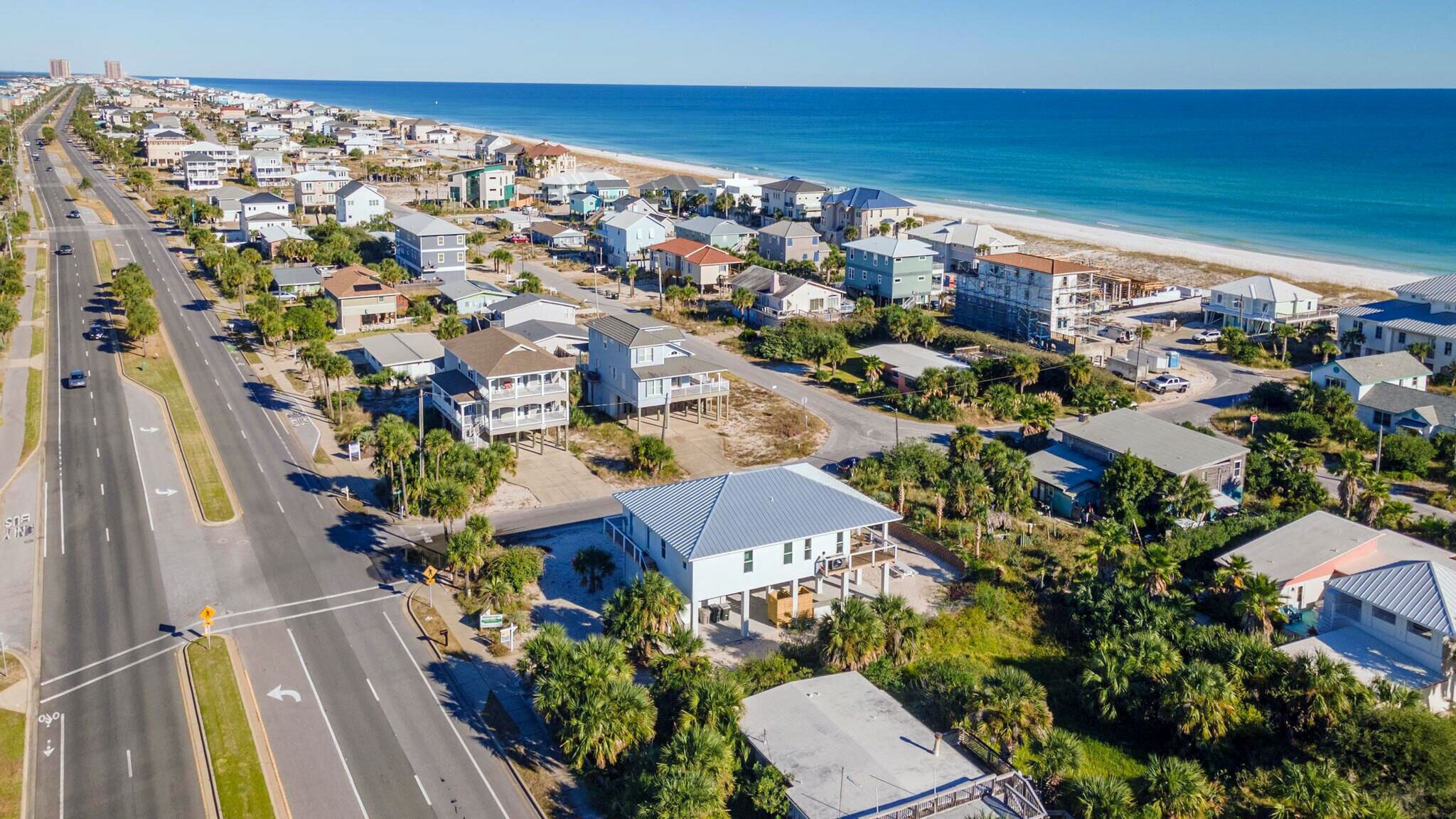 A coastal residential area with houses, a road, and a beach.