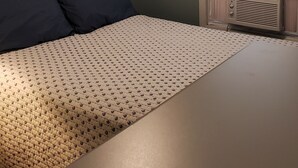 Un dormitorio con cama, ventana con persianas y una lámpara en el techo.