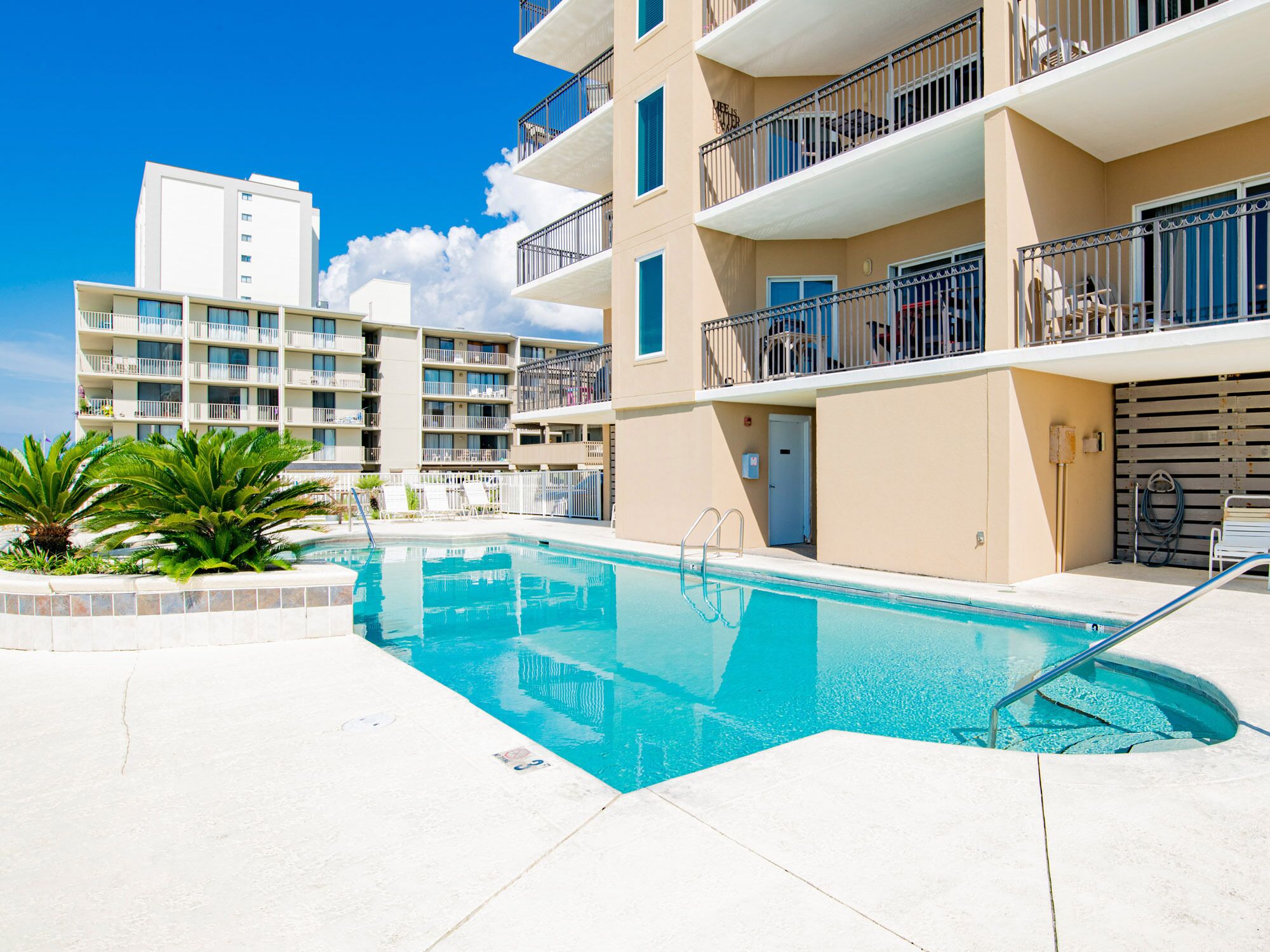 A swimming pool with a clear blue water, surrounded by a white tiled deck.