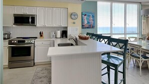 Een moderne keuken met witte kasten, roestvrijstalen apparatuur en een groot eiland met barstoelen.