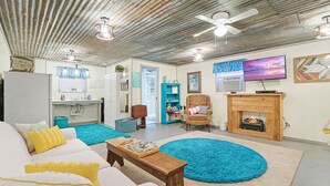 A living room with a white sofa, blue rugs, a wooden coffee table, a fireplace, and a television. - Come On Inn | Close to Downtown Wimberley! (Wimberley)