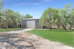A single-story building with a large garage door, surrounded by trees and a well-maintained lawn.