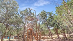 A wooden observation tower with a staircase, surrounded by trees in a natural setting. - Come On Inn | Close to Downtown Wimberley! (Wimberley)