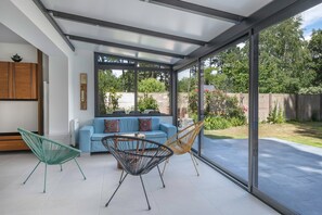 A modern patio with a blue sofa, two chairs, and a glass enclosure. - 100m from sea, house 6 adults & 4 kids (Mesquer)