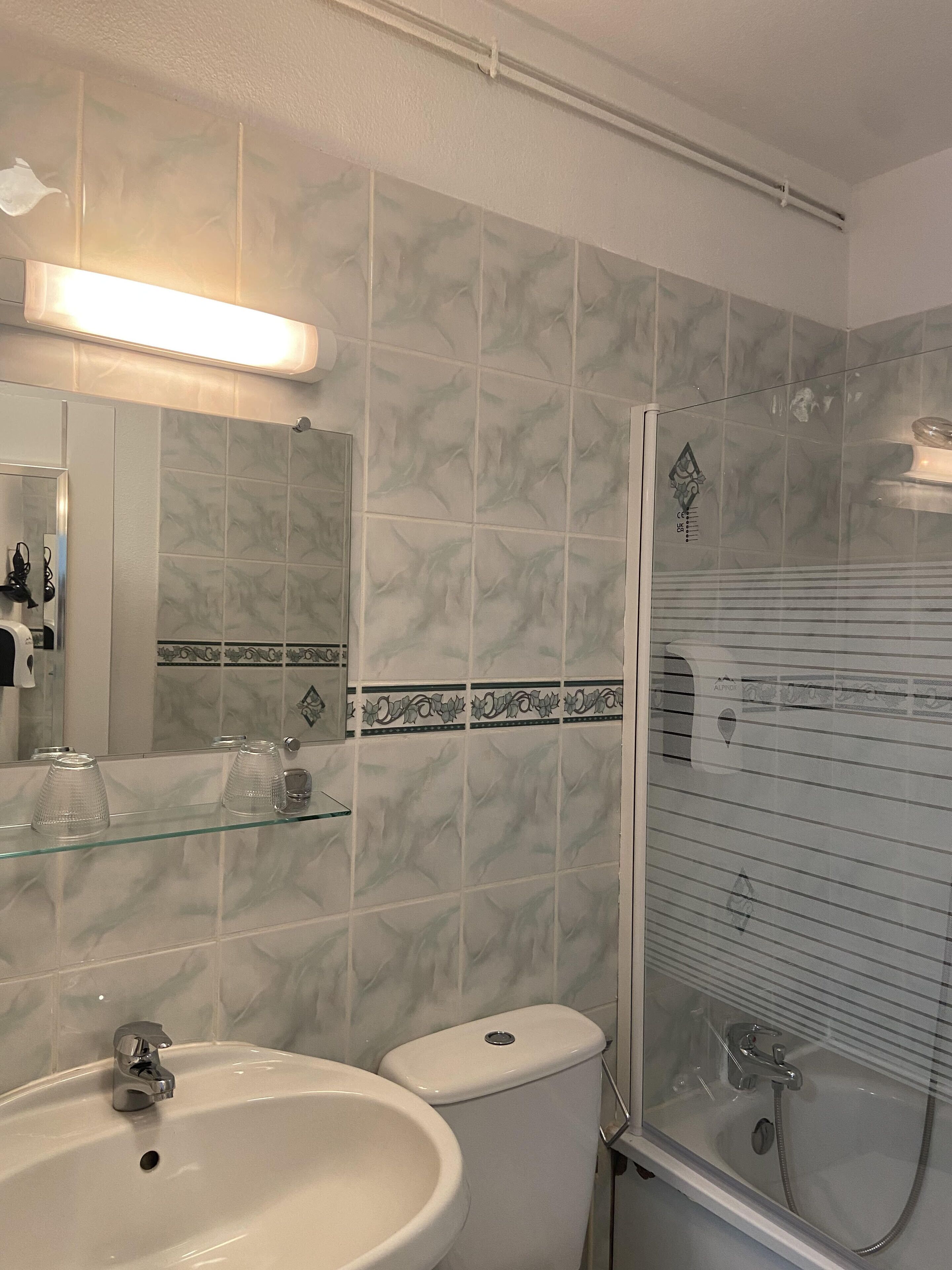 A bathroom with a sink, toilet, and glass-enclosed shower.