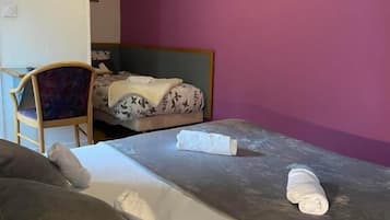 Quarto com duas camas, uma cadeira, uma televisão e TV fixada na parede.