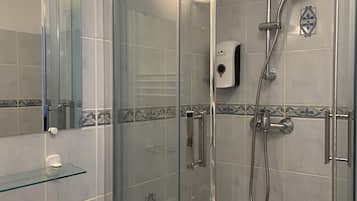 Une salle de bain moderne avec une douche à parois de verre, un lavabo avec un verre et un distributeur de savon.