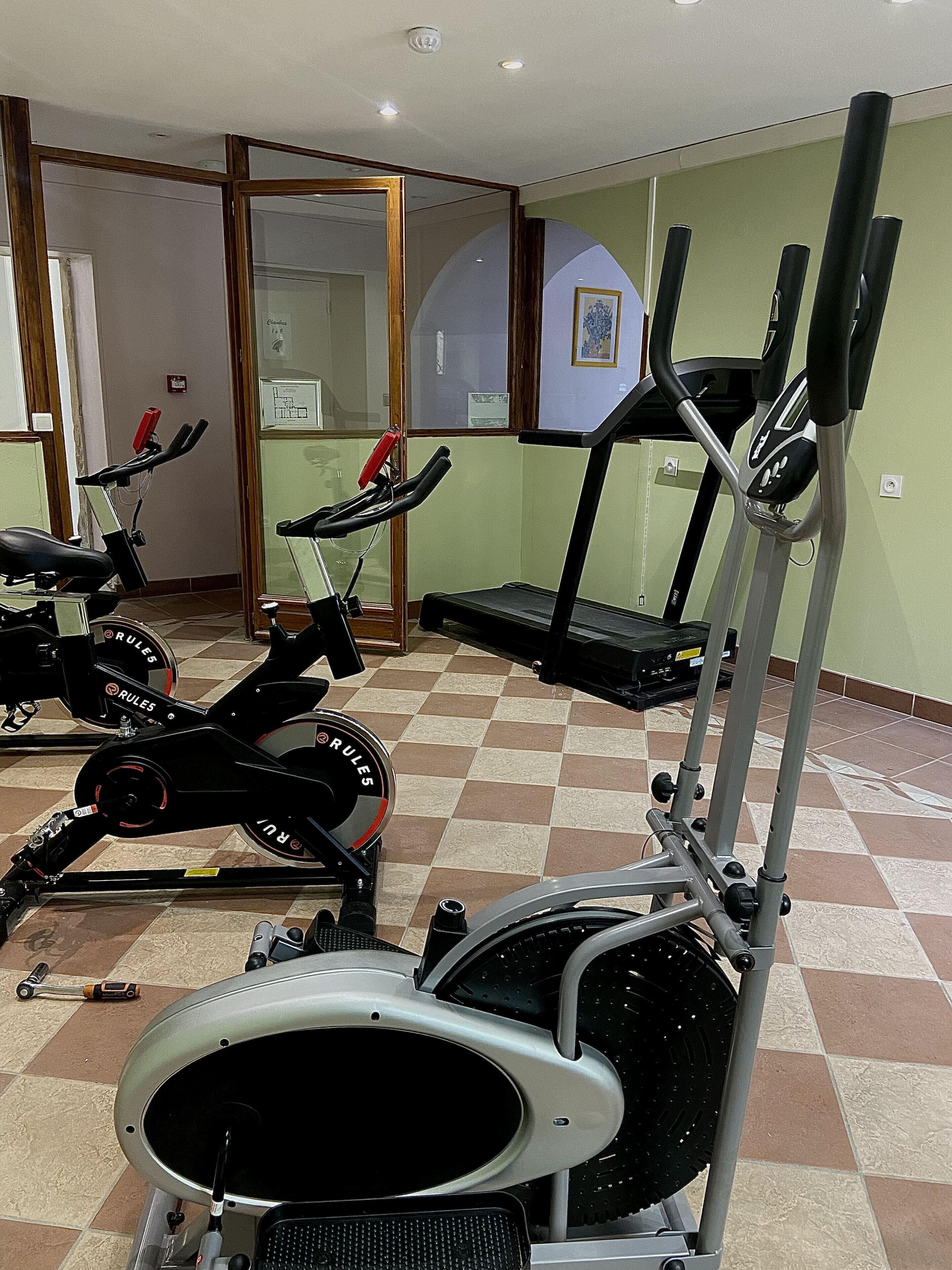 Un gimnasio con bicicletas estáticas, cinta de correr y máquina de remo.