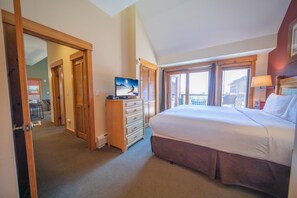 Ein Schlafzimmer mit einem großen Bett, einem Schminktisch, einem Fernseher und einem Balkon mit Blick.