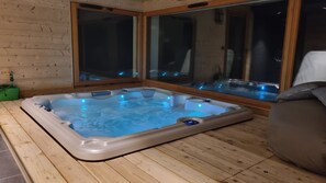 A hot tub with a wooden floor and a window.