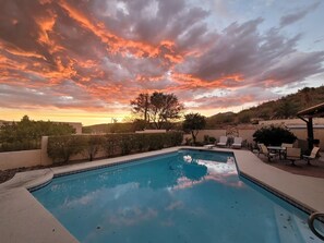 A swimming pool with a view of a sunset and a hilly landscape. - Suite Stay with Heavenly Views (Tucson)