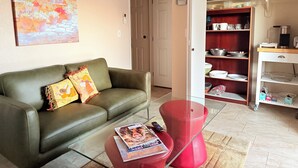 A living room with a green sofa, a red ottoman, and a magazine on the ottoman.