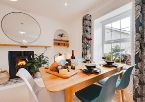 Enjoy meals in this inviting dining area with a central table, wood-burning stove, and scenic views.
