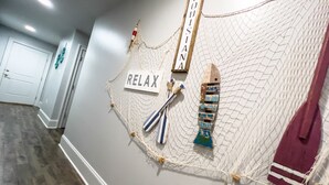 Ein Flur mit Wandkunstinstallation, die ein Netz mit dem Wort "LOUISIANA" und ein Schild mit der Aufschrift "RELAX" zeigt.