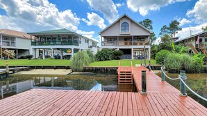 A waterfront property with a dock, a grassy lawn, and a house with a balcony.