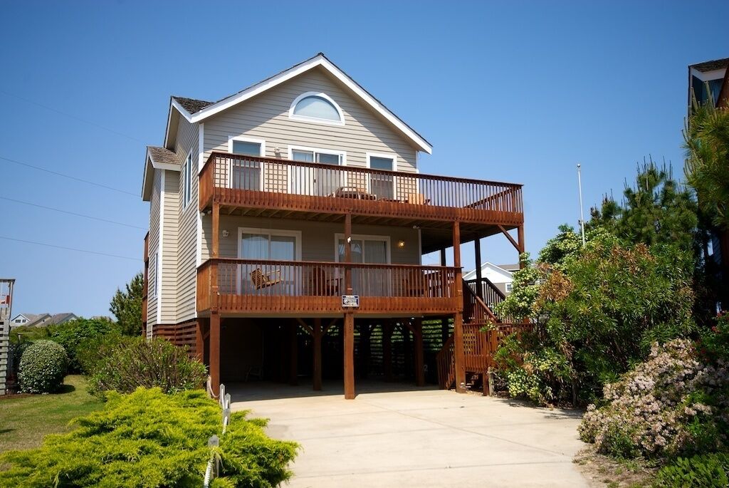 A two-story house with a balcony, a garage, and a well-maintained garden.