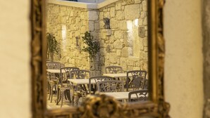 A mirror reflecting an outdoor dining area with stone walls and tables. - Ala Da Vinci Hotel Alaçatı (Cesme)