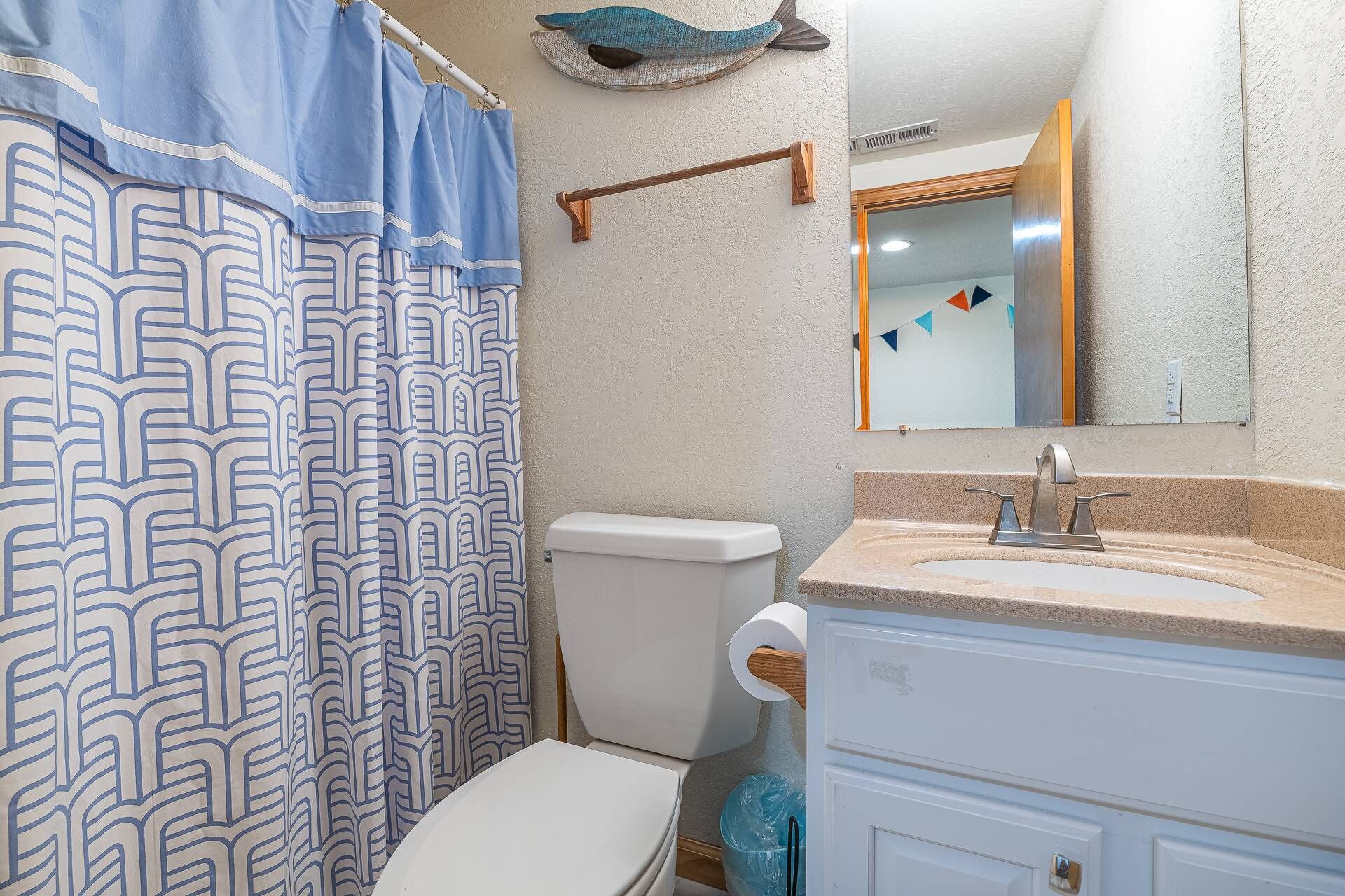 A bathroom with a toilet, a sink, and a shower curtain with a geometric pattern.