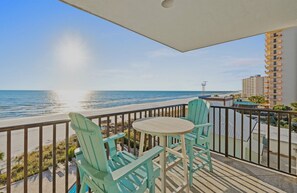 A balcony with two chairs and a table overlooking a beach. - FREE Chairs! Gulf Front 1 bed - 2 bath Condo PW510 (PANAMA CITY Beach)
