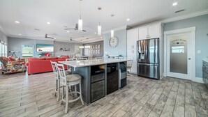 A modern kitchen with a central island, built-in appliances, and a dining area with bar stools. - Your Private Paradise Awaits! (Gulf Shores)