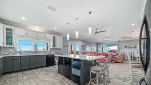 A modern kitchen with a large island, grey cabinets, and a tiled backsplash. - Your Private Paradise Awaits! (Gulf Shores)