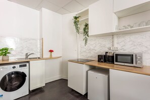 A compact kitchen with a washing machine, a microwave, a small refrigerator, and a sink. - Merveil - Family Suite - Marais - Sebastopol III (Paris)