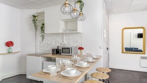 A modern kitchen with a marble backsplash, a built-in microwave, and a wooden dining table set for six. - Merveil - Family Suite - Marais - Sebastopol III (Paris)