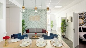 A dining area with a table set for four, a sofa, and a decorative wall. - Merveil - Family Suite - Marais - Sebastopol III (Paris)