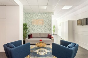 A modern living room with a sofa, two armchairs, a coffee table, and a patterned rug. - Merveil - Family Suite - Marais - Sebastopol III (Paris)