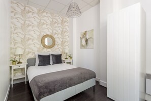 A bedroom with a bed, nightstands, a mirror, and a wall with a leaf pattern. - Merveil - Family Suite - Marais - Sebastopol III (Paris)