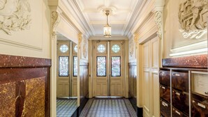 A hallway with ornate doors, patterned floor tiles, and a ceiling with decorative moldings. - Merveil - Family Suite - Marais - Sebastopol III (Paris)
