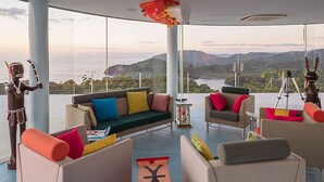 Una sala de estar moderna con un amplio ventanal que ofrece vistas a un paisaje pintoresco, amoblada con sofás y cojines coloridos.