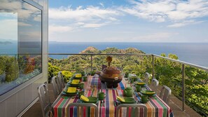 A dining table set with green plates and yellow napkins, overlooking a scenic view of the ocean and hills. - VIP amazing private island (Veraguas)