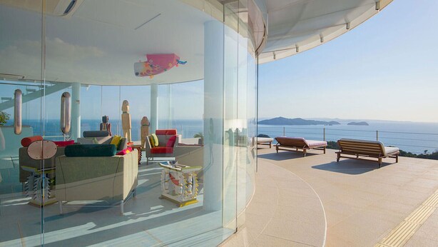 Un interior moderno con un muro de cristal que ofrece vistas panorámicas al océano.