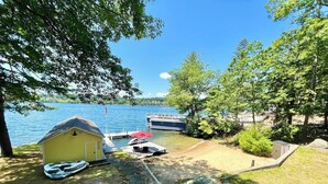 Una proprietà sul lago con un molo, un piccolo capanno giallo e una barca.