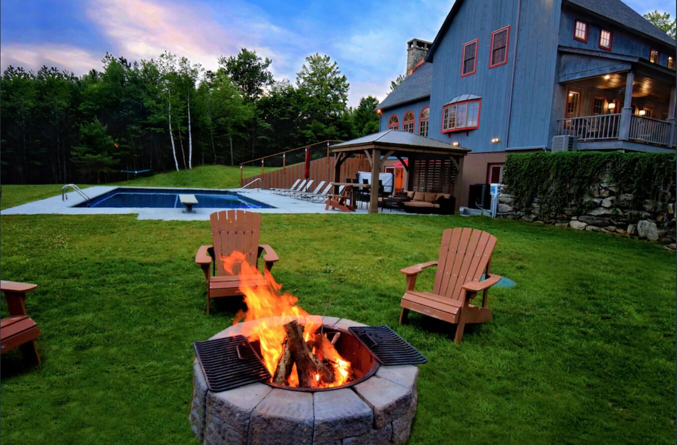 A backyard with a fire pit, outdoor seating, and a swimming pool.