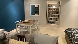 Een moderne kamer met een eethoek, een boekenkast en een bed.