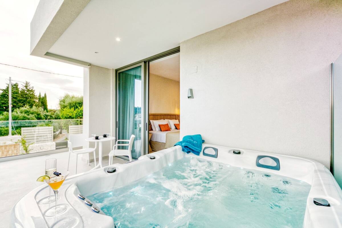 Uma área interna moderna com banheira de hidromassagem e porta de vidro que dá para uma área de estar externa.