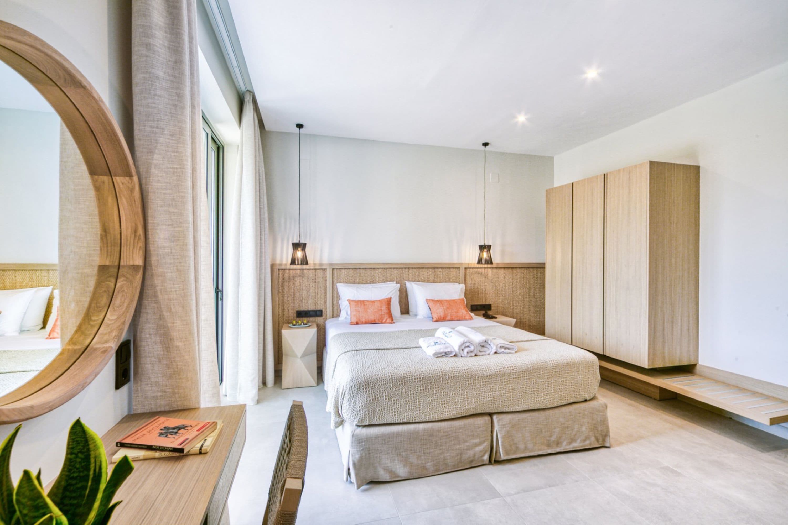 Una habitación de hotel moderna con una cama grande, mesitas de noche, un espejo y un armario.
