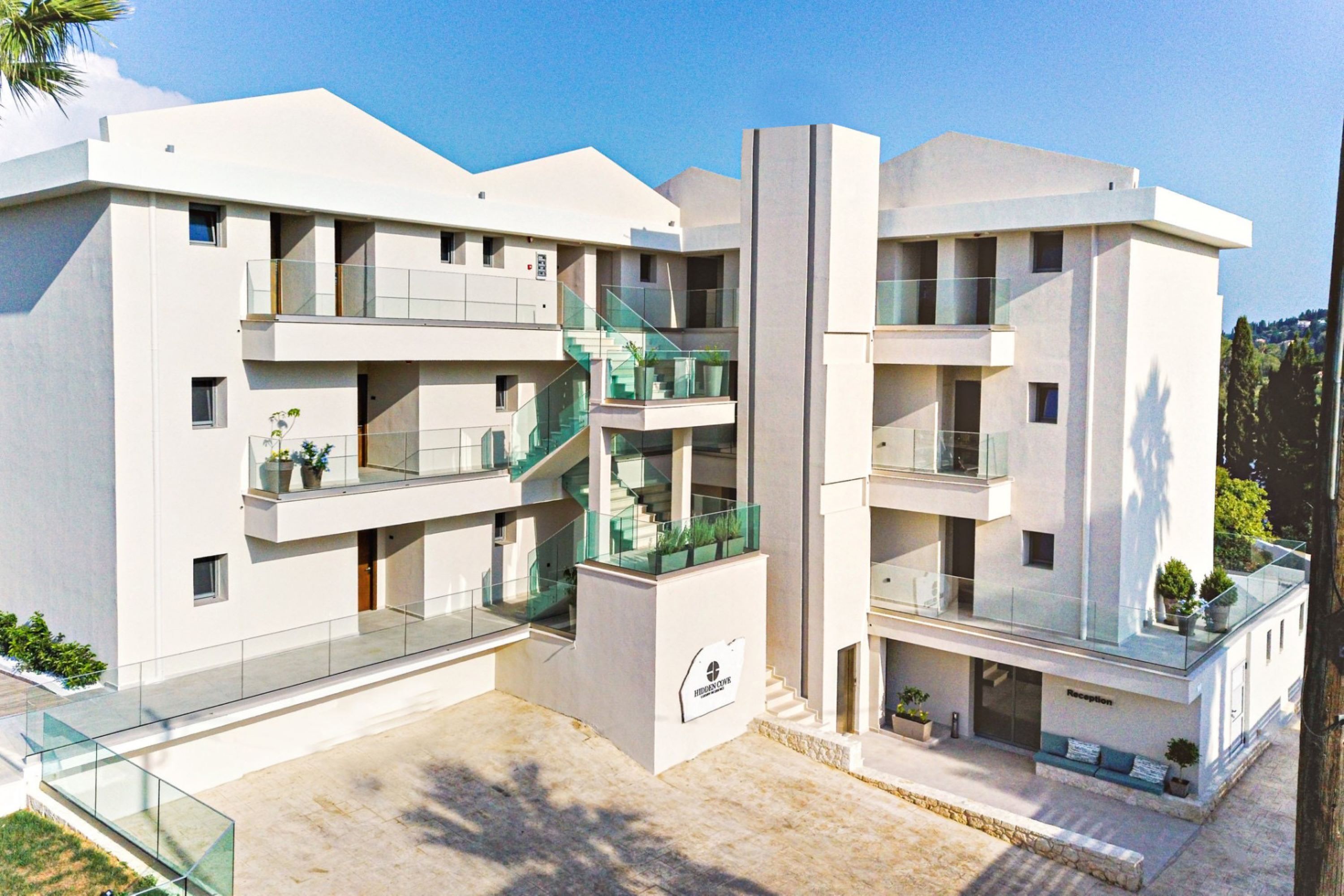 A modern multi-story hotel with a reception area, glass railings, and a staircase.