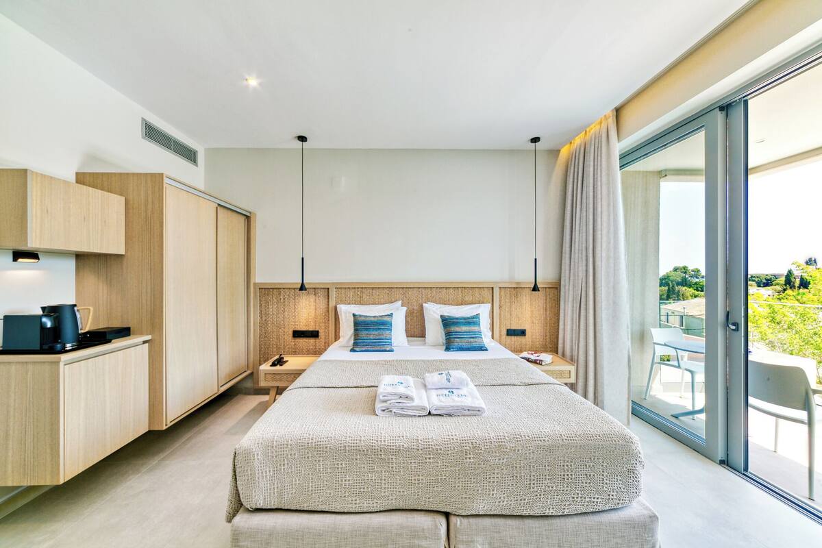 Quarto de hotel moderno com uma cama grande, uma mesa de trabalho e vista para o exterior.
