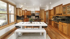 A modern kitchen with wooden cabinets, a built-in microwave, and a dining area with a white table and bench. - Warm Chalet in the beautiful Rocky Mountains (Carbondale)