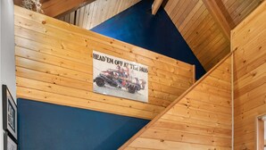 Un escalier en bois, avec un mur bleu et une affiche représentant un véhicule.