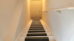A staircase with white walls and a door at the top. - Idyllic carriage house private 2 car garage W/D (Newark)